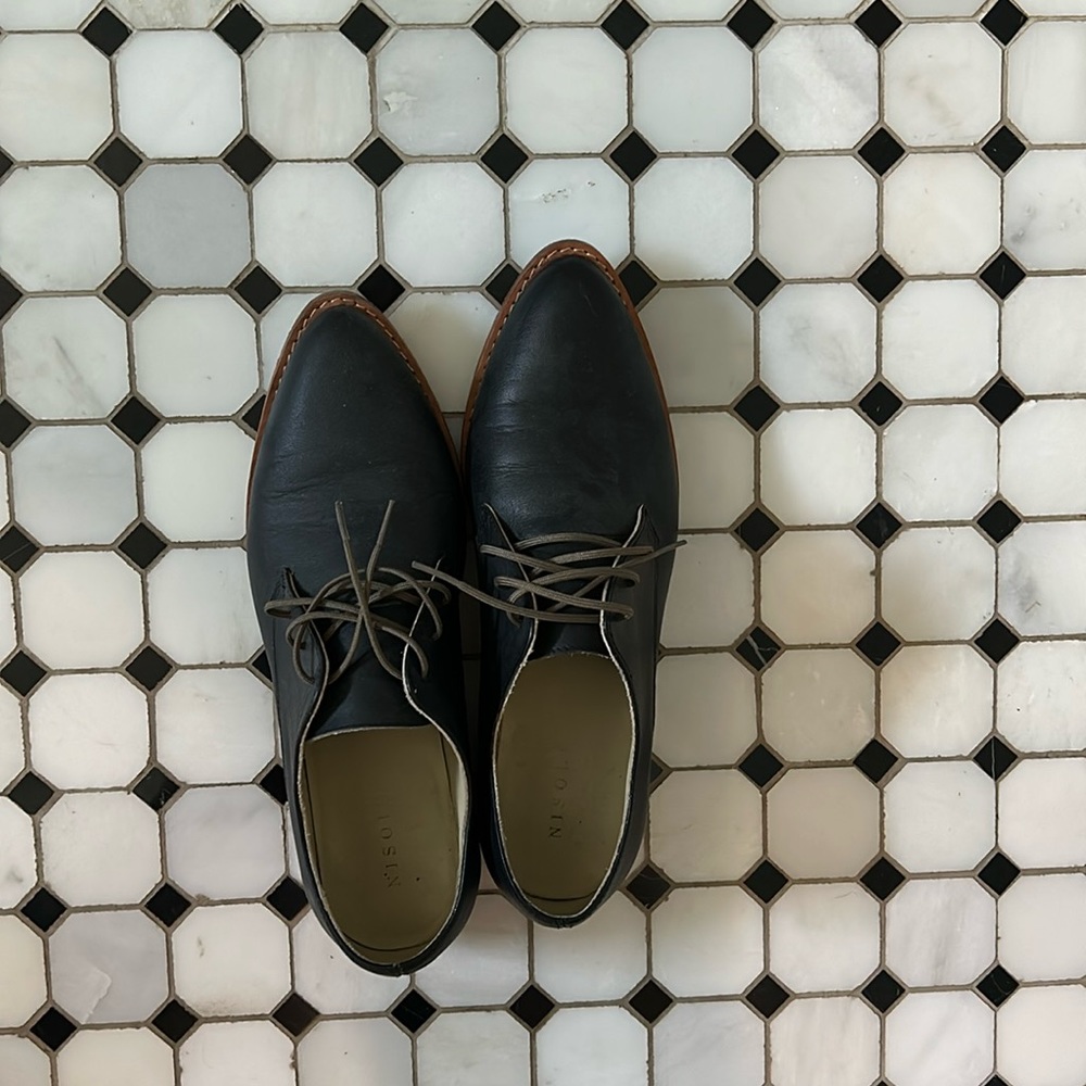 Lace up black matte loafers with dark wood sole.
